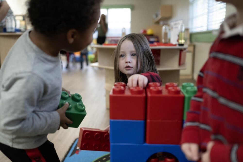 child stacking blocks with teacher