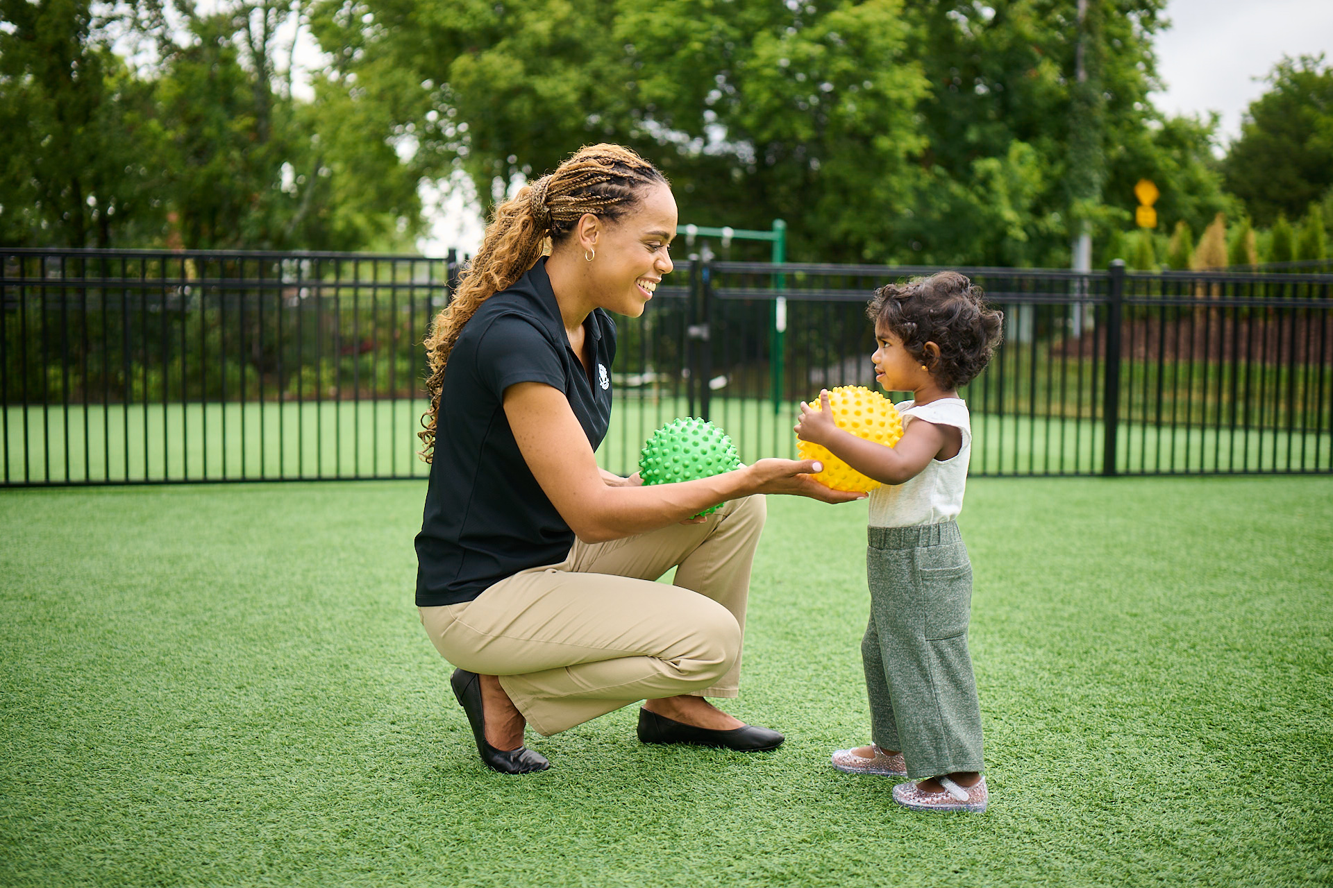 teacher and child playing with ball on playground