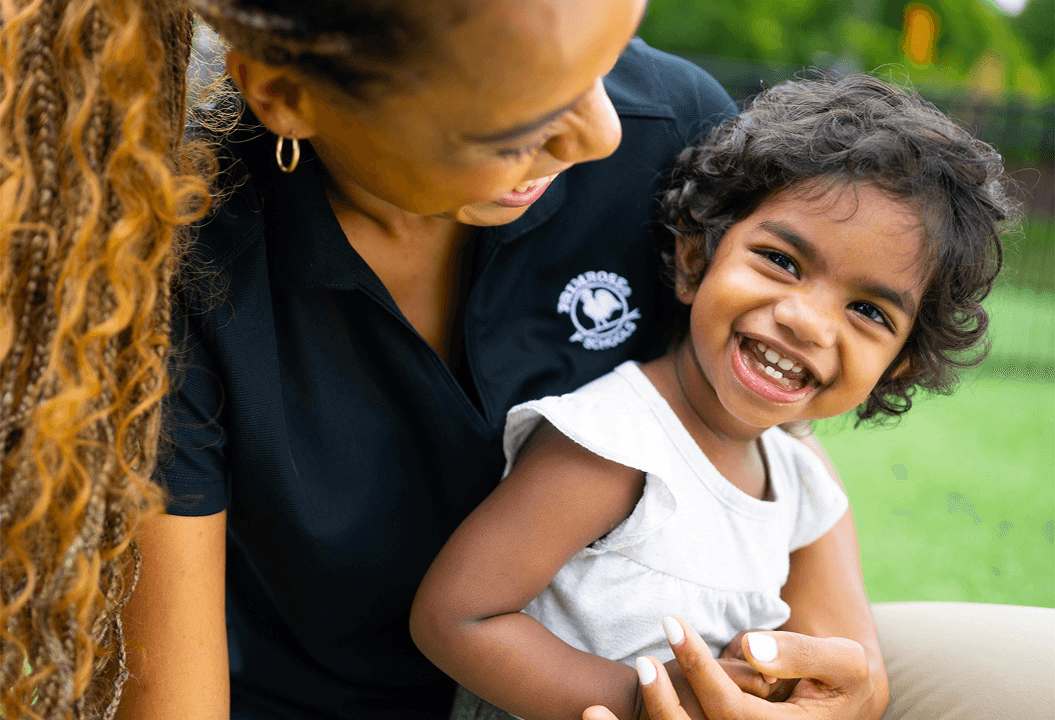 early preschool teacher playing on the playground with child