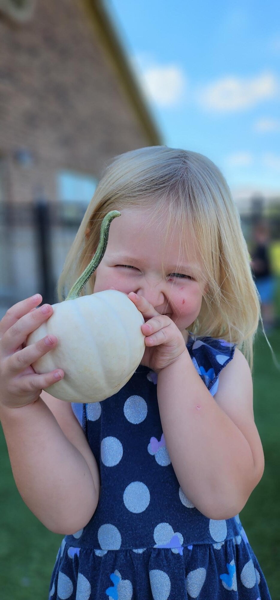 Smiling child holding a pumpkin in the garden where the children learn hands on about living plants
