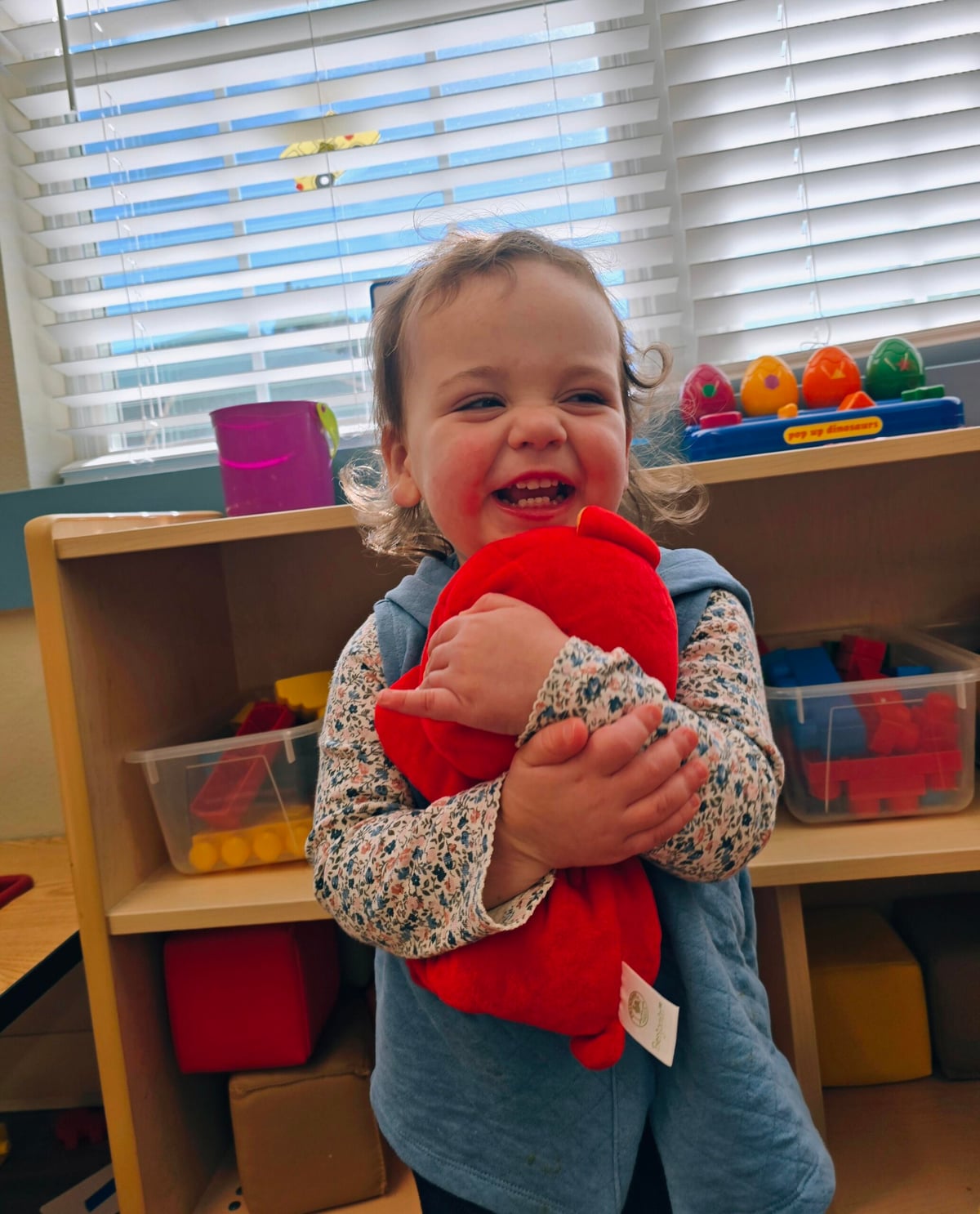 Young girl showing kindness and affection while hugging a puppet at a preschool in Keller, Texas