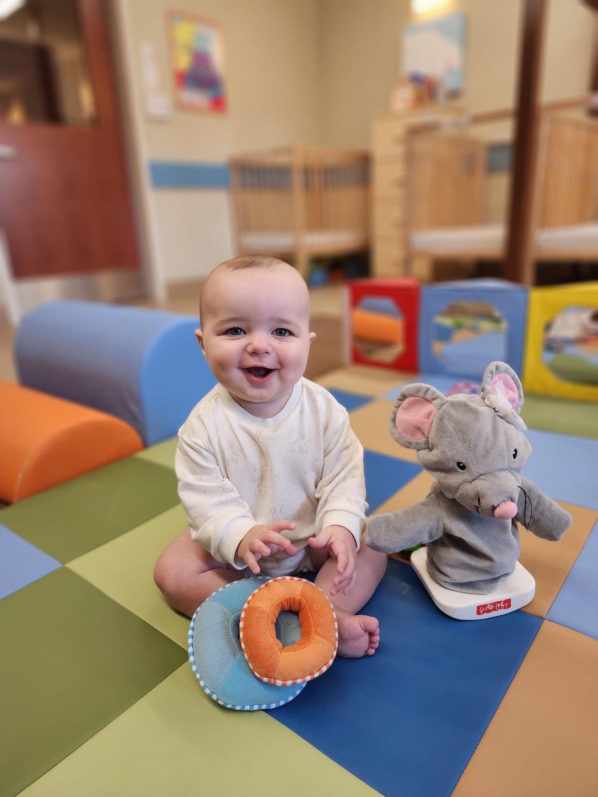 Infant lifting colorful rings up and down using their small motor skills during activity time 