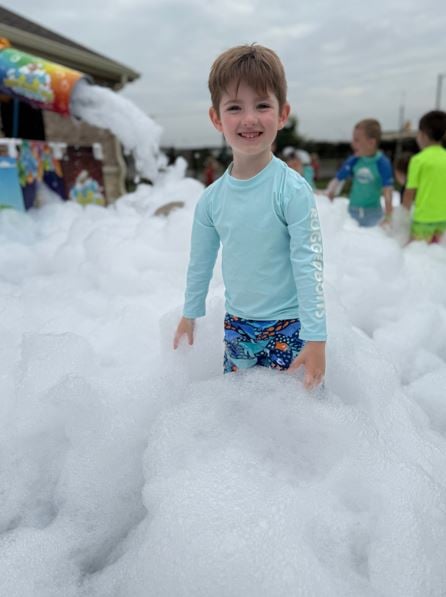 Happy child at summer camp enjoying a foam party at Primrose School NW fort Worth