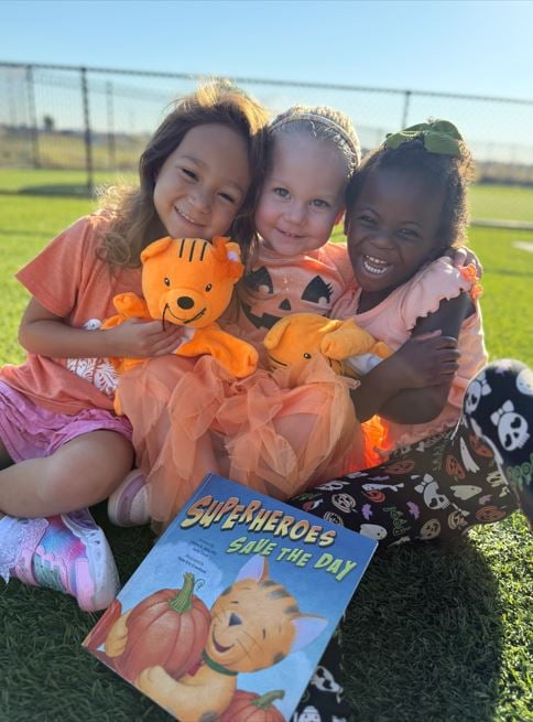 Smiling Prekindergartners playing together outside to learn about cooperation 