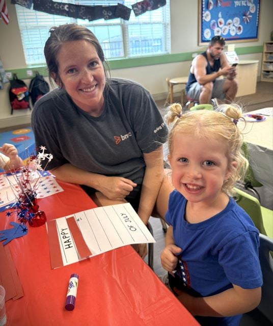 Mother and Daughter smiling together creating a craft during their classroom Fourth of July Party near Berkshire in Fort Worth, TX