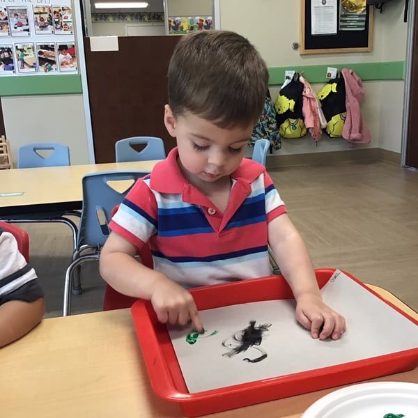 2 year old fine motor skills practice while finger painting 