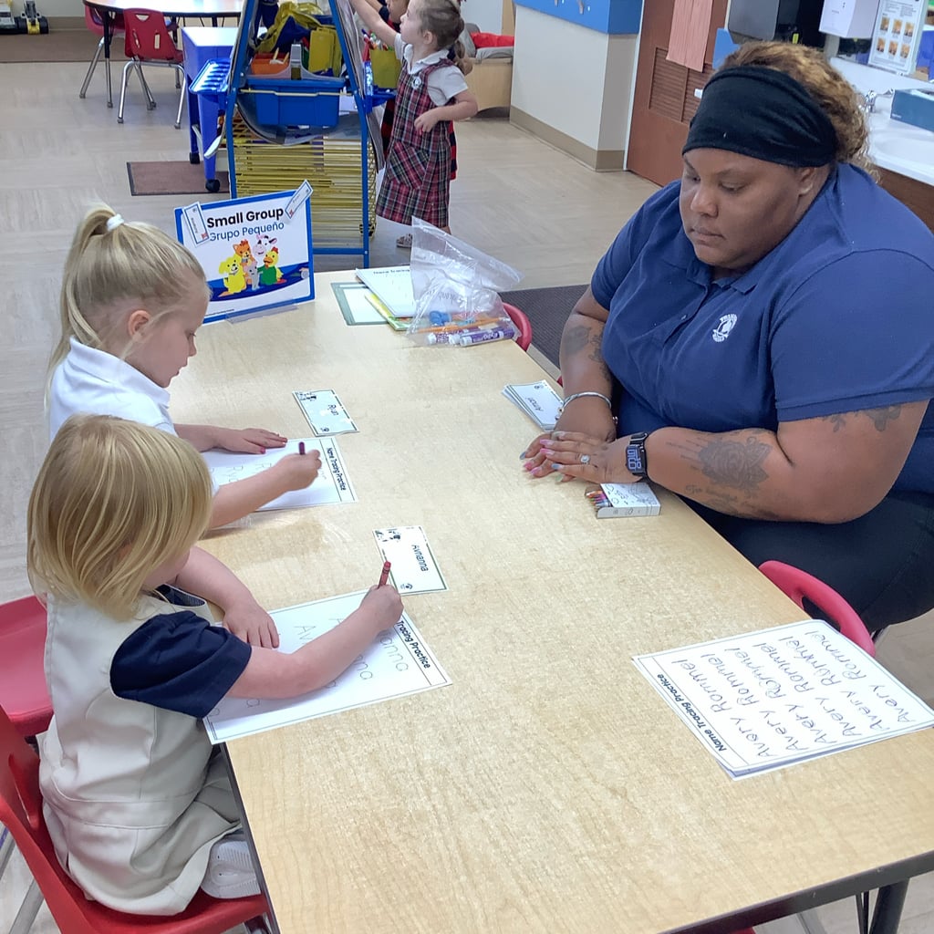 Children at a table learning to write their names