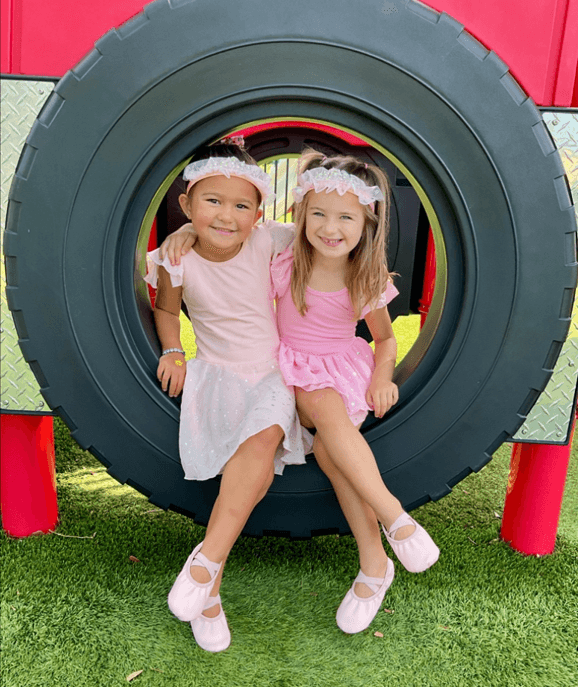 children sitting on a tire swing