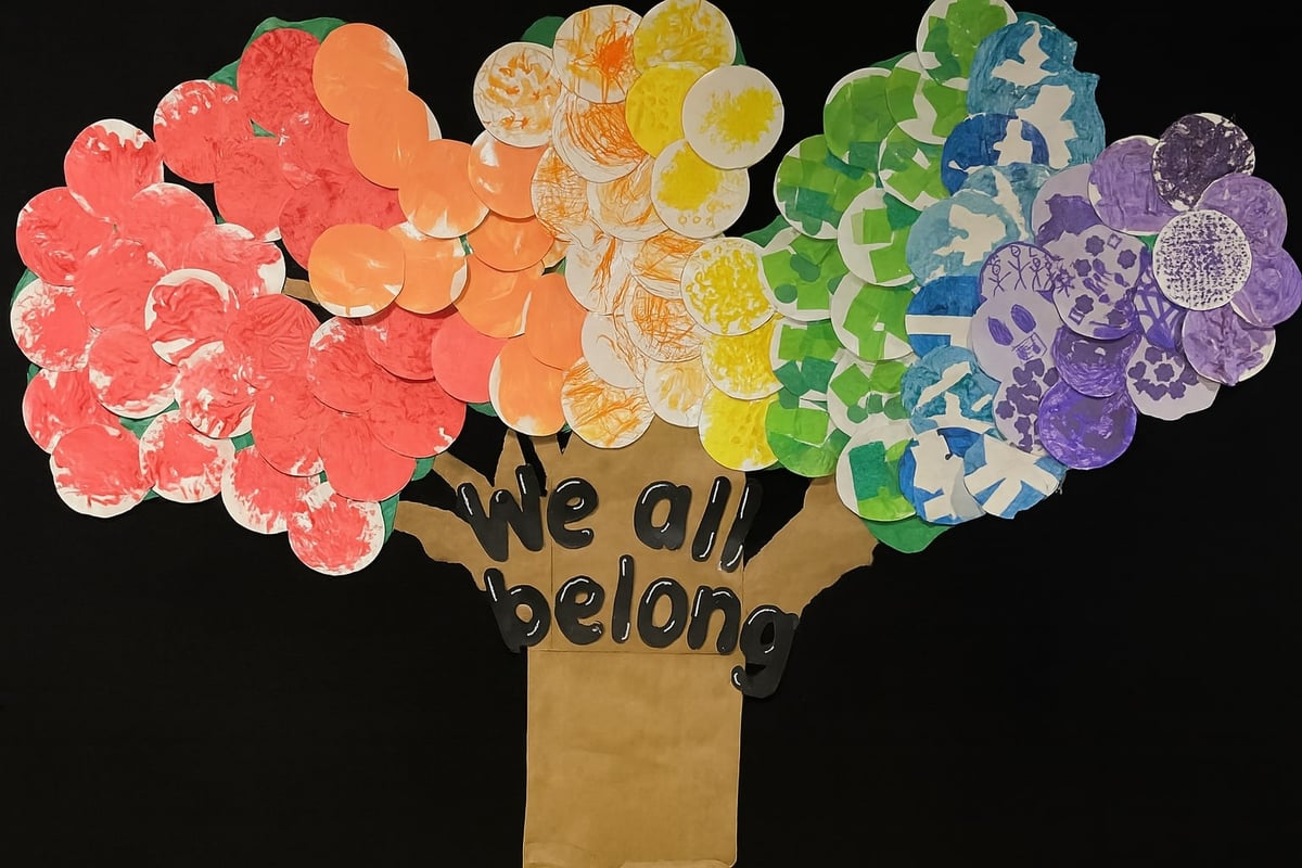 Handmade classroom mural of a tree with colorful paper circles and 'We all belong' message, created by children at Primrose School of Eagan