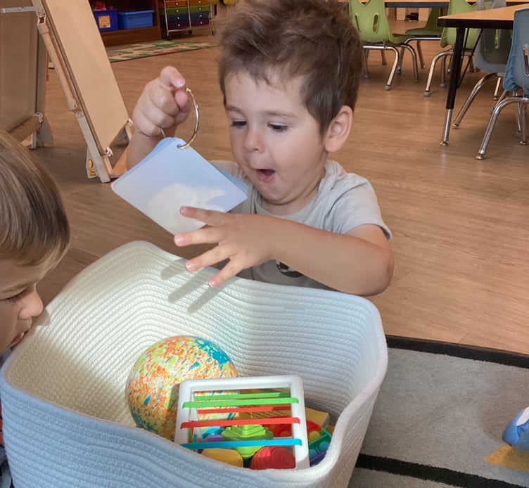 excited child looking at a picture from a basket full of toys