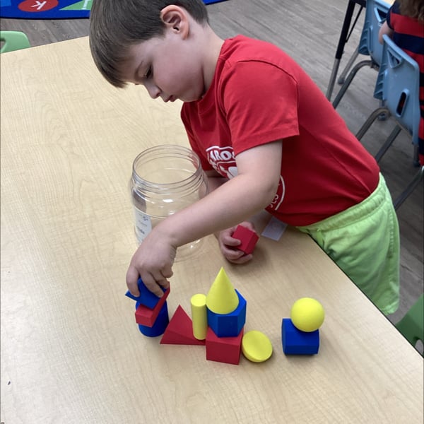 child in red shirt playing with blocks