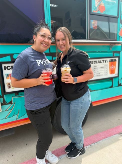 Two staff enjoying drinks from a coffee truck at school during Teacher Appreciation Week for community support