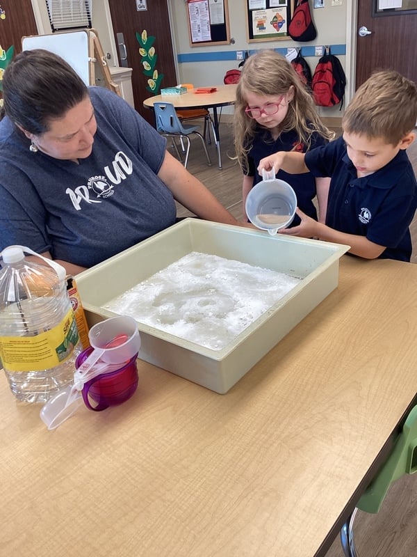 Pre-K pouring liquid into a bin