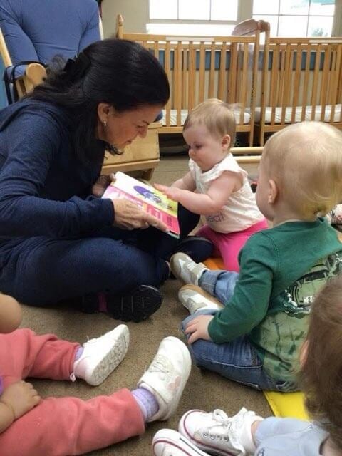 A baby interacting with their grandparent reading a book