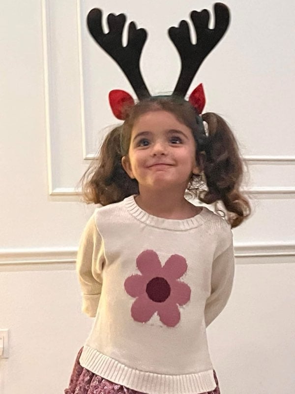 A child smiling wearing a reindeer antler headband