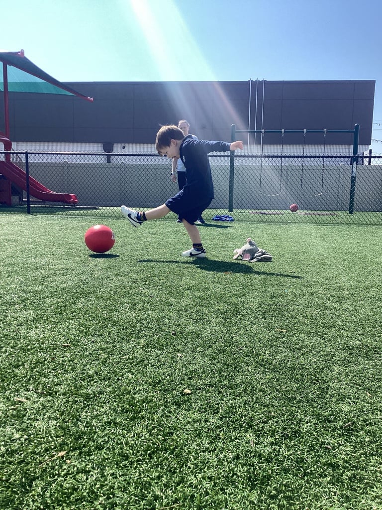 child kicking red ball