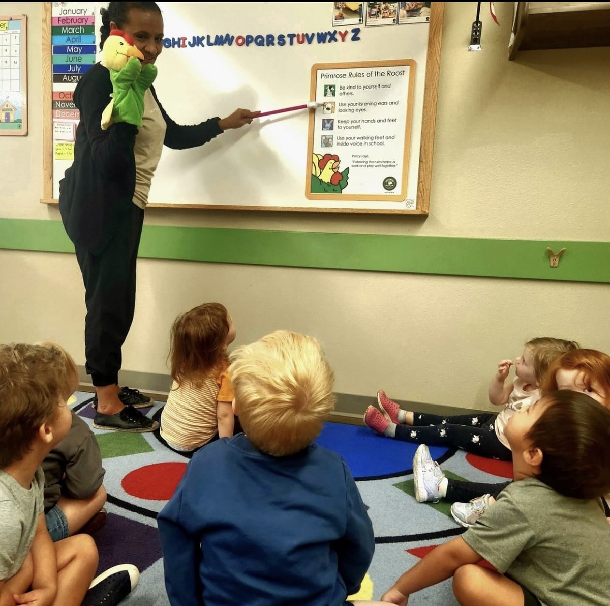 Teacher reading Percy's rules of the roost to students with Percy the Rooster hand puppet