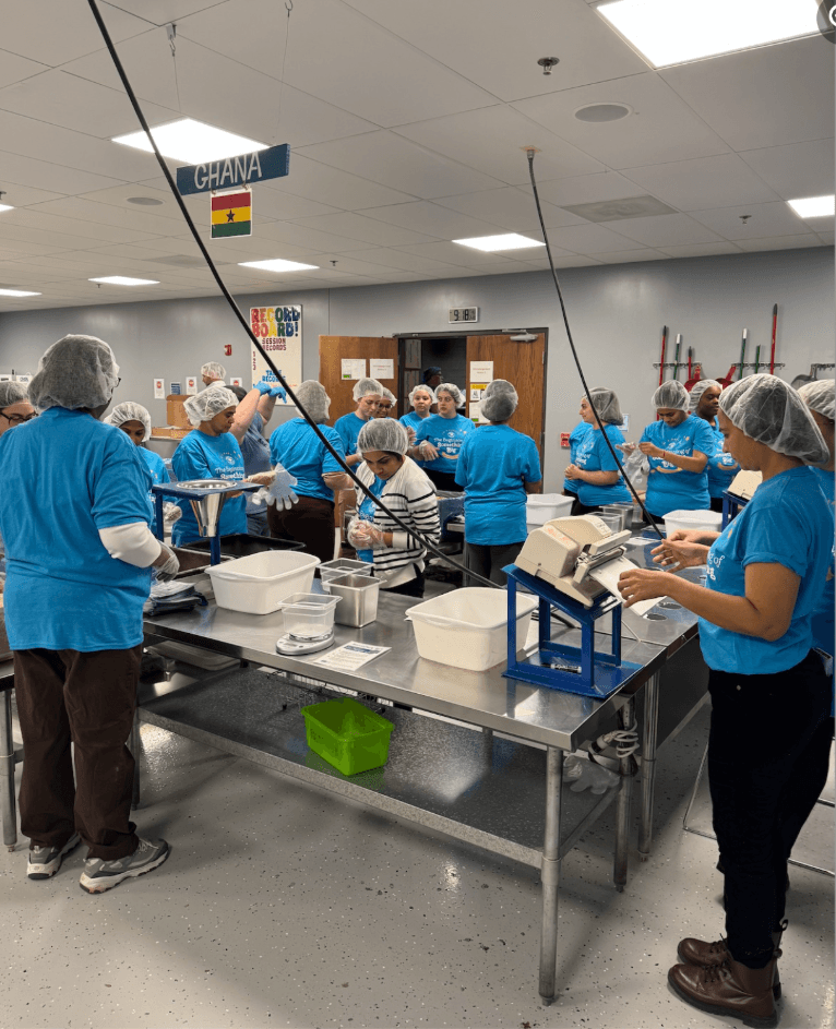 women in blue shirts standing around table 