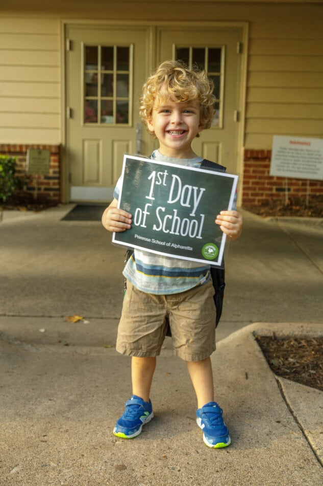 child holding a sign that says first day of school