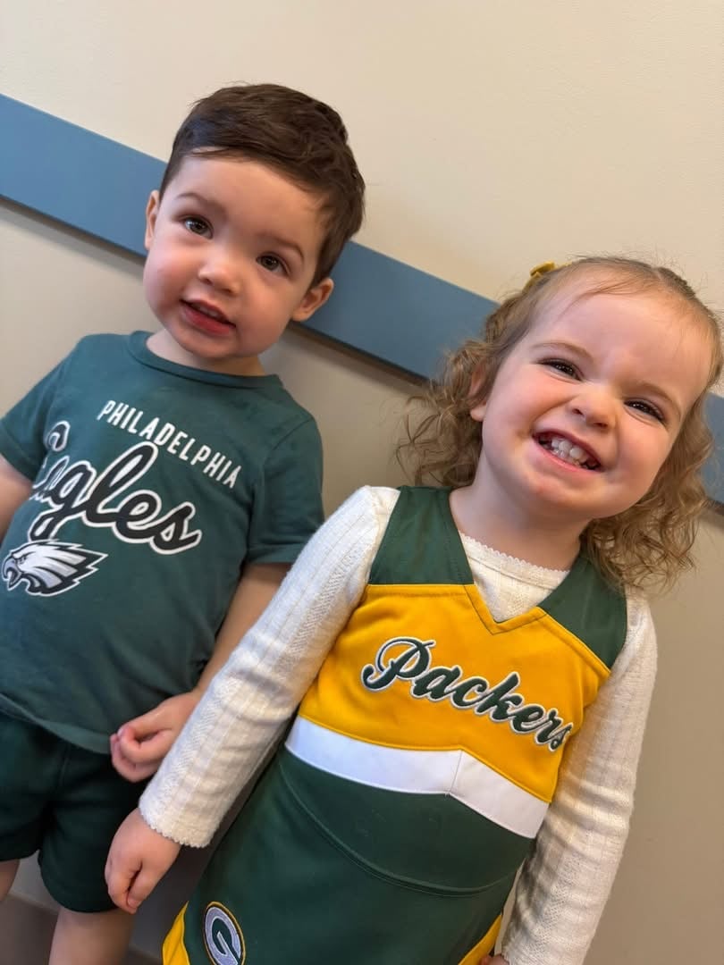 boy in an eagles t-shirt and girl in a packers cheerleading outfit 