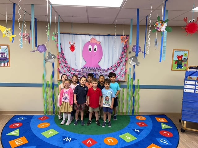 students standing in front of a white board with a purple octopus