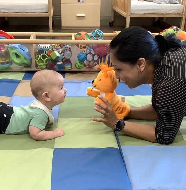 Loving Teacher playing with a happy baby to encourage tummy time!