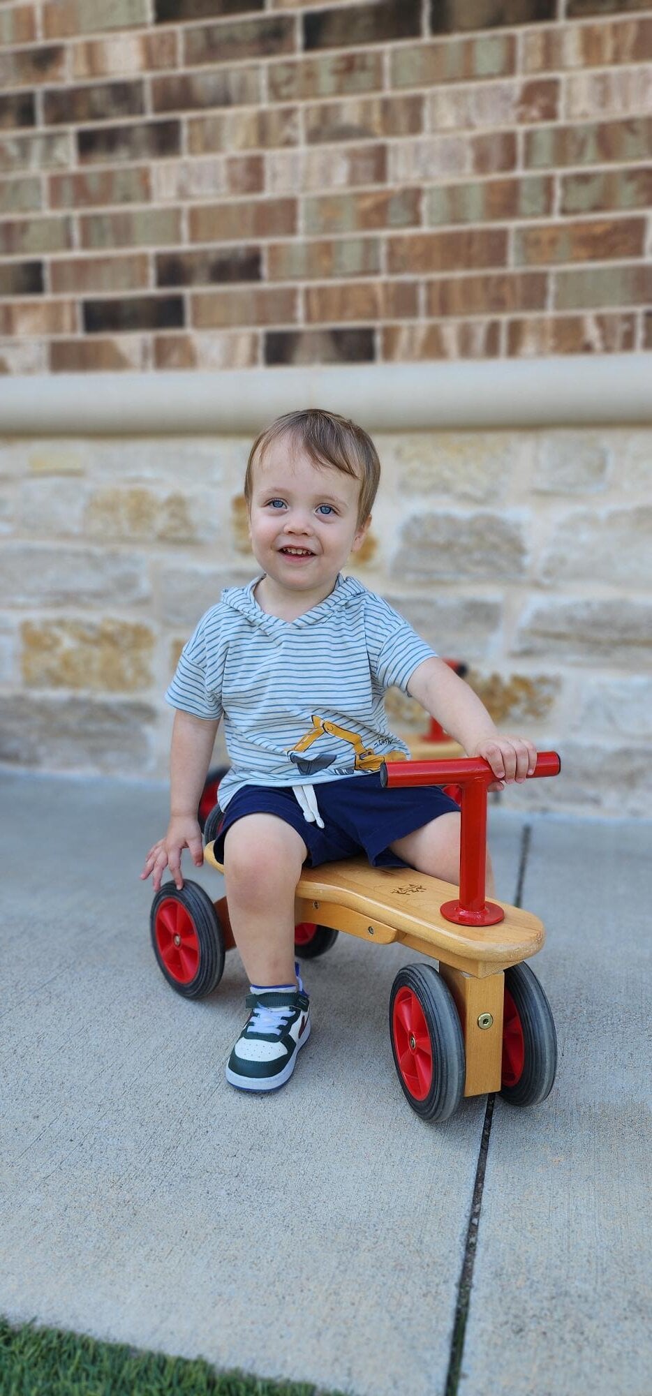 Toddler riding a bike during outdoor play at daycare to develop gross motor skills