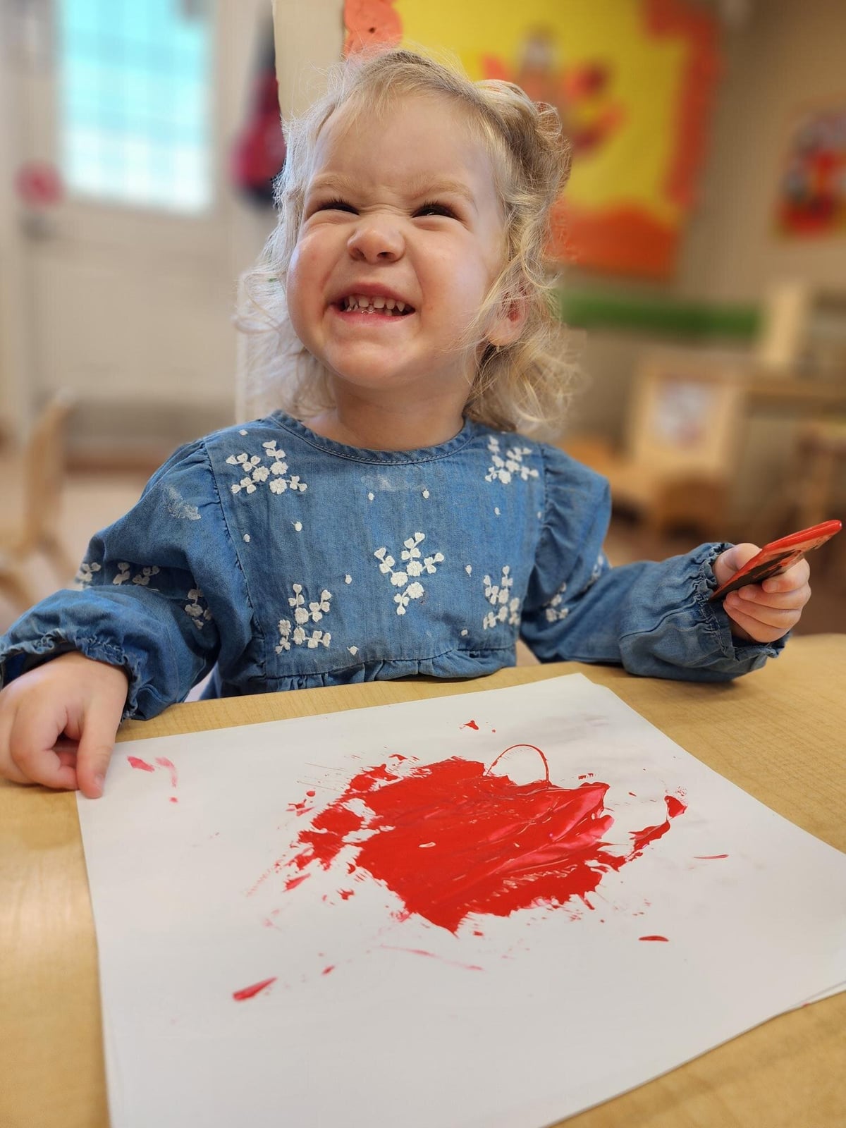 Child developing fine motor skills while painting in class in a small group