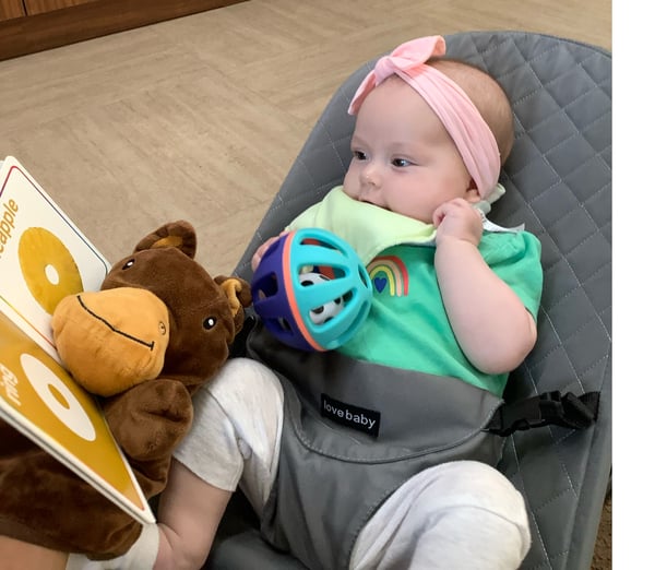 Infant looking at a shape-themed book and matching items in that shape on the pages