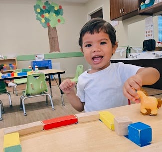 Smiling toddler child playing with blocks during center time at Primrose School at Heritage in Fort Worth, Texas.