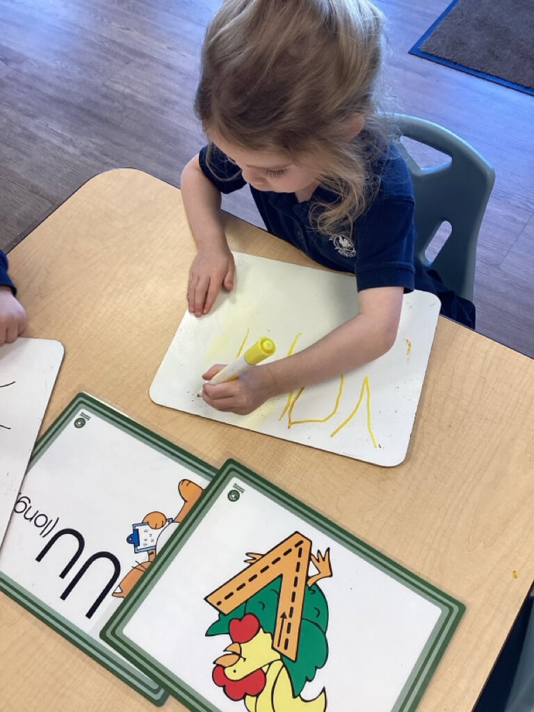 child writing lettter U and V