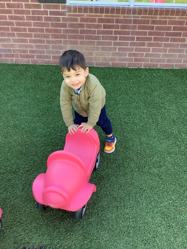 little boy on playground pushing a cart