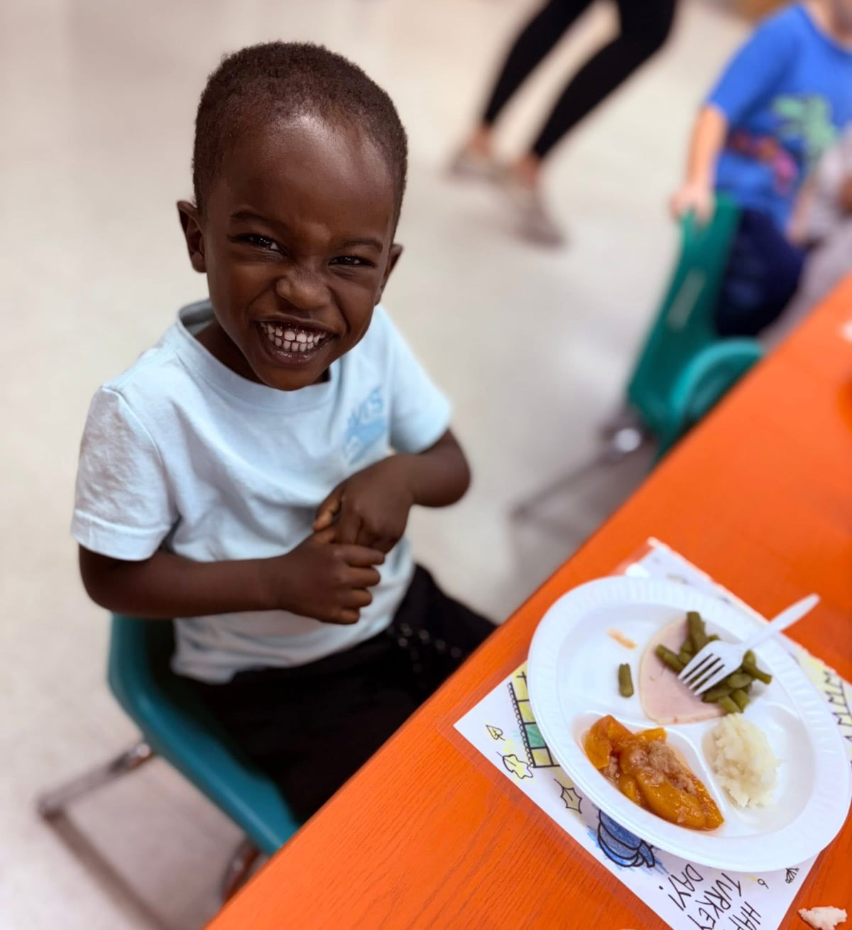 Child smiling in front of a Thanksgiving plate of food
