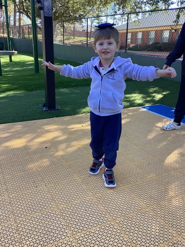 little boy balancing a bean bag on his head with his arms outstretched