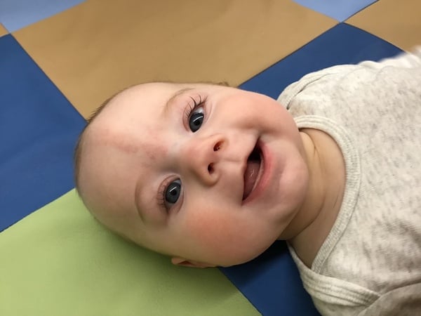 A baby smiling up at the camera