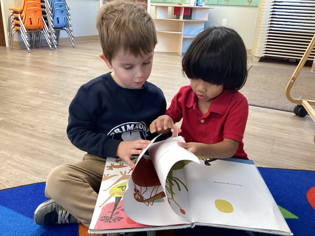 Two children sitting reading a book