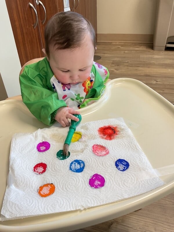 Young baby holds a paint brush
