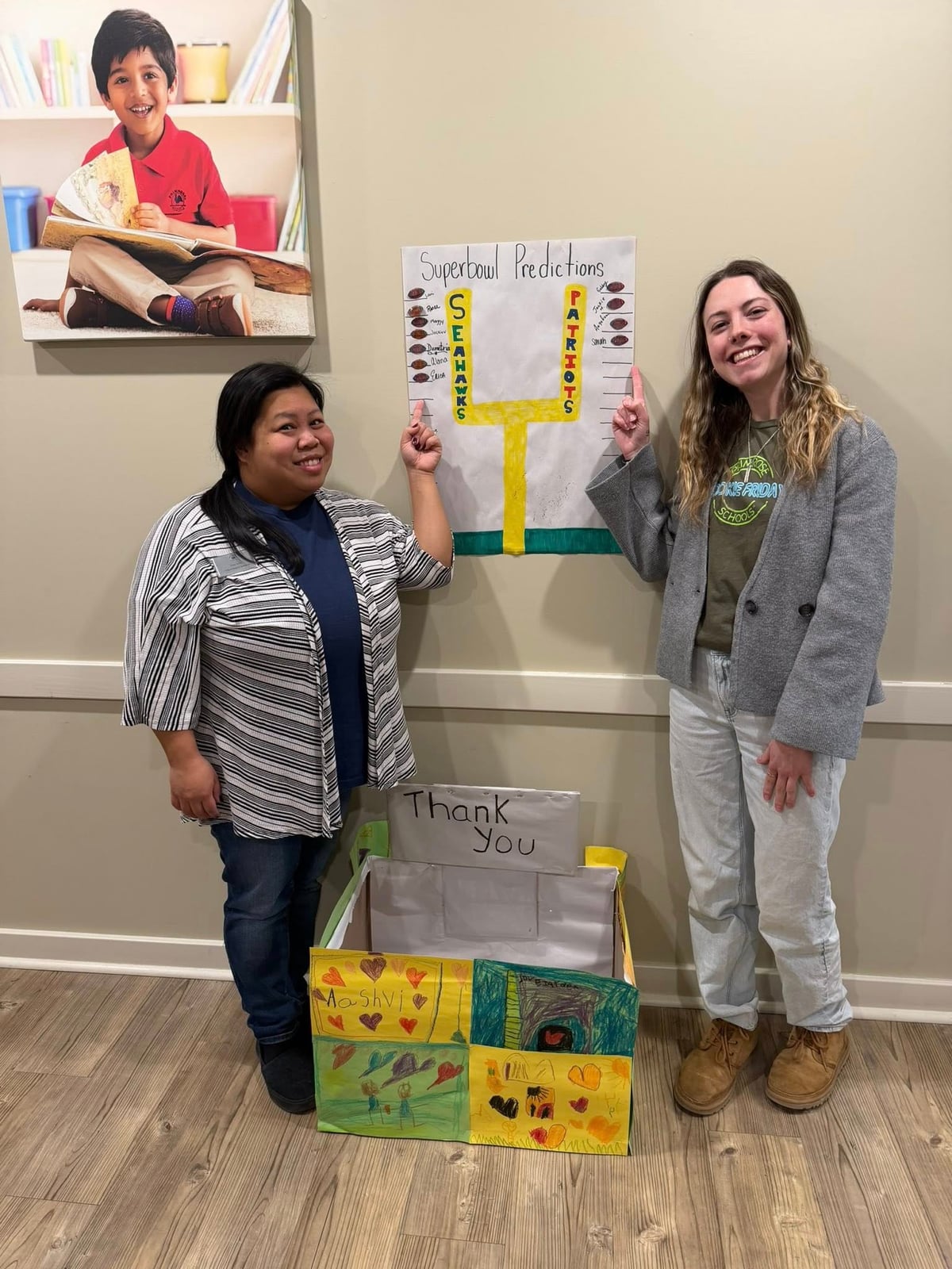 Two women stand next to a football chart