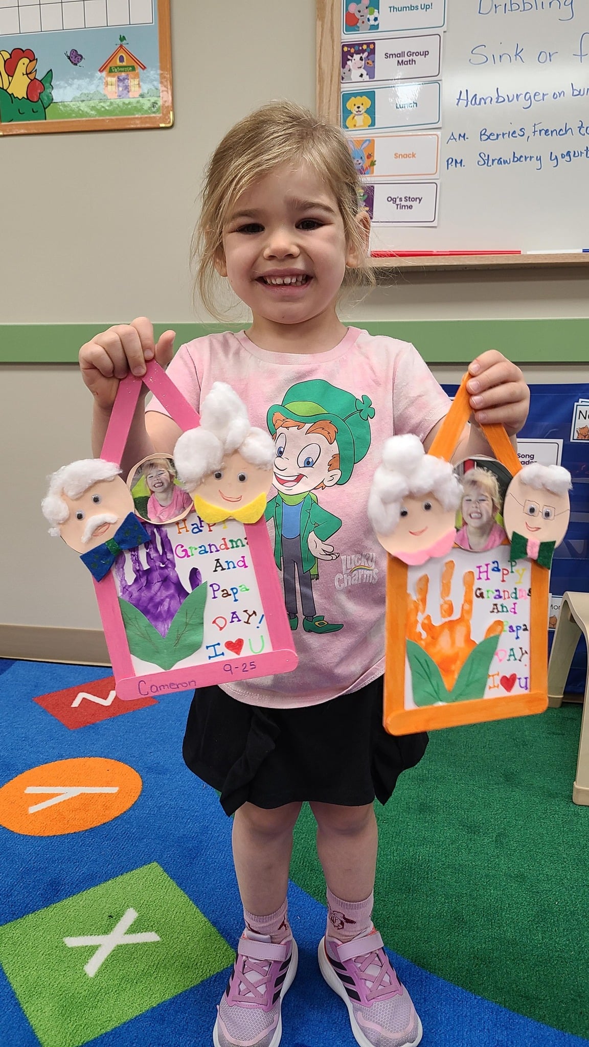 girl with pink shirt holding to grandparents day crafts