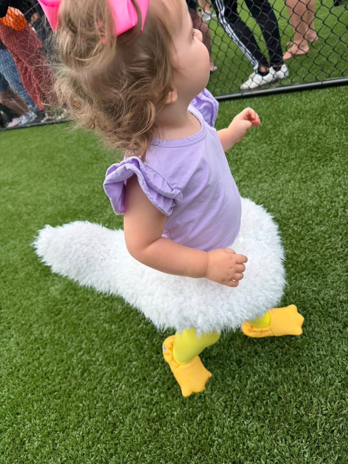 child in duck costume walking on grass