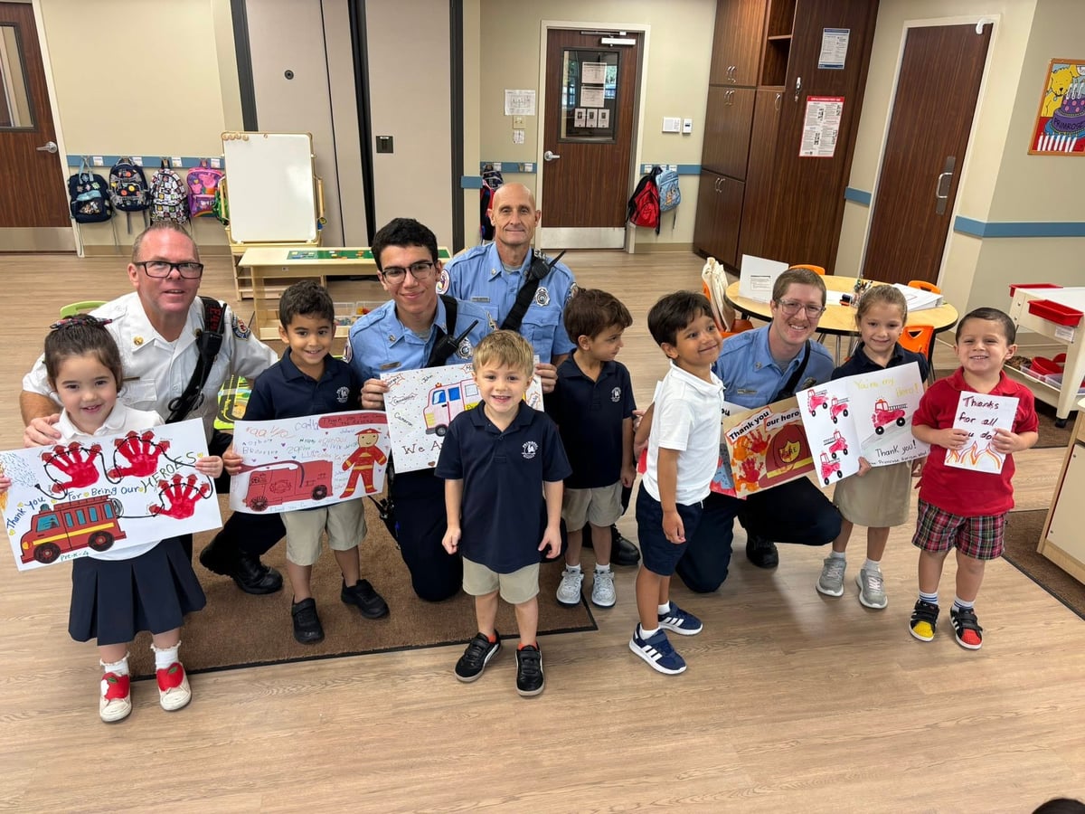 students holding up cards with firefighters inside of a classroom