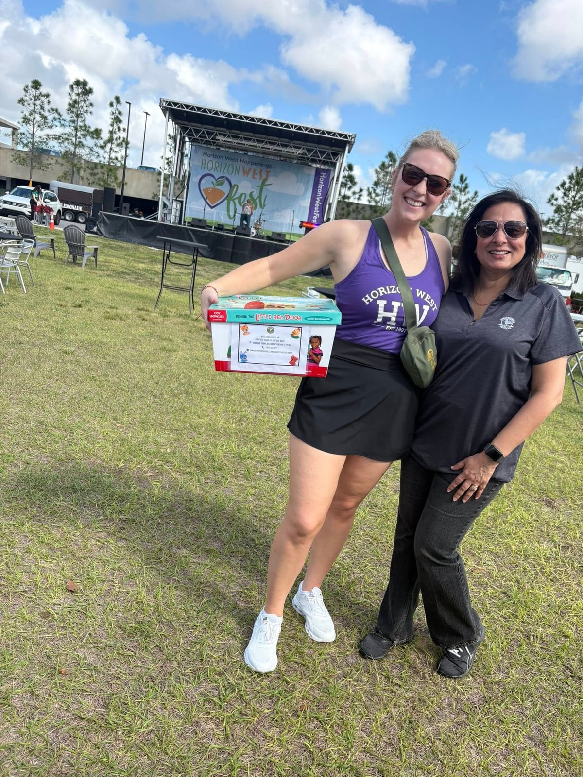 two women one in a purple shirt and one in a gray shirt in a field outside
