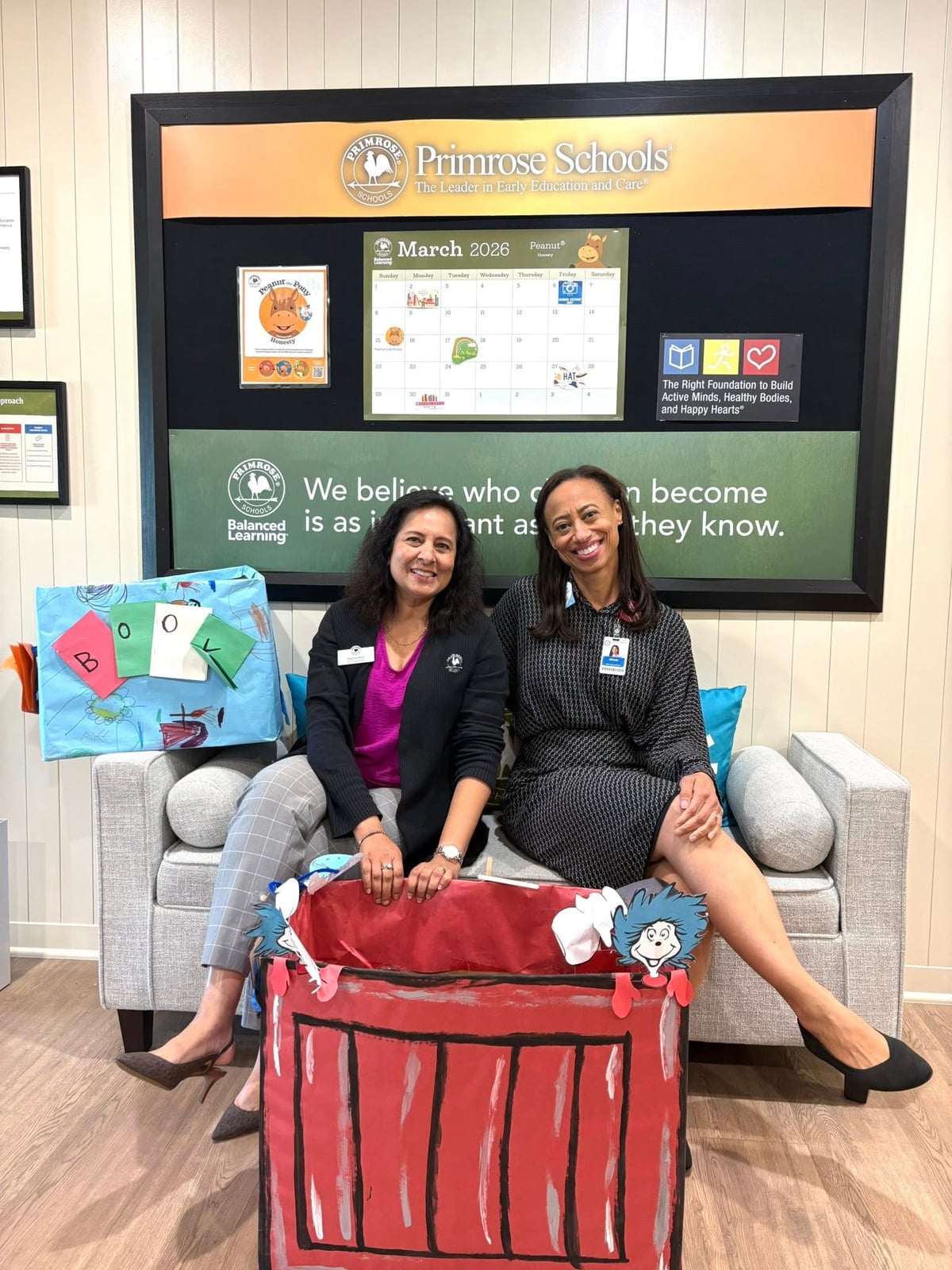 two women sitting on a bench with a red Dr. Seuss box in front of them